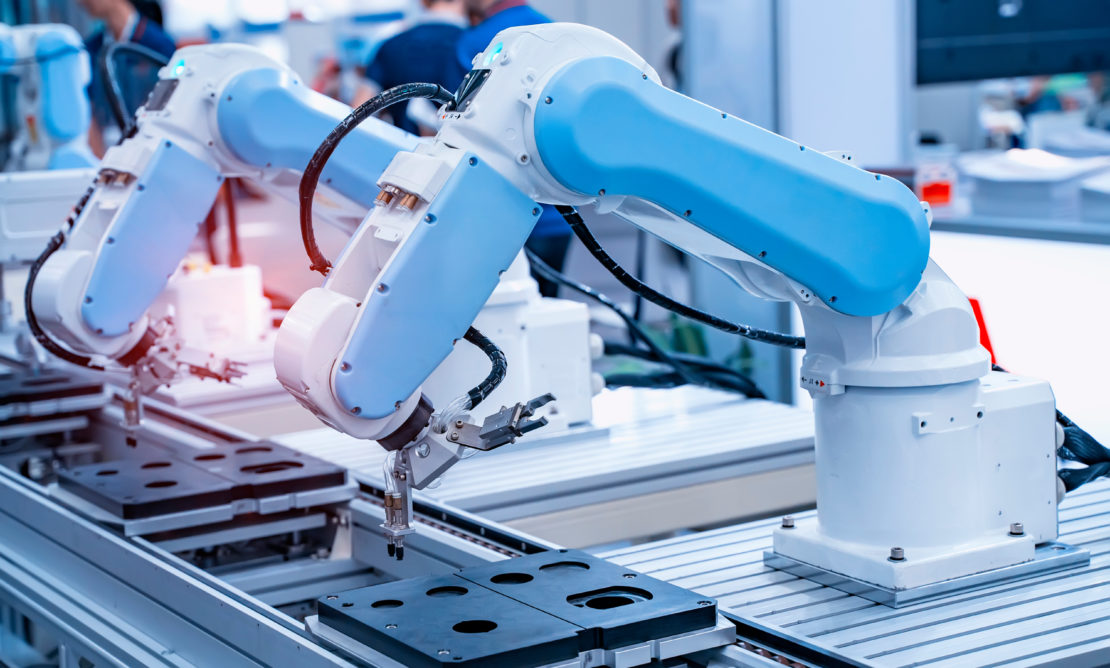 two blue and white robotic arms working together on an assembly line