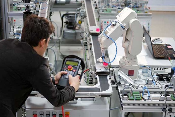 Schneider & Company - A technician calibrates a robotic arm in a modern industrial automation setting.